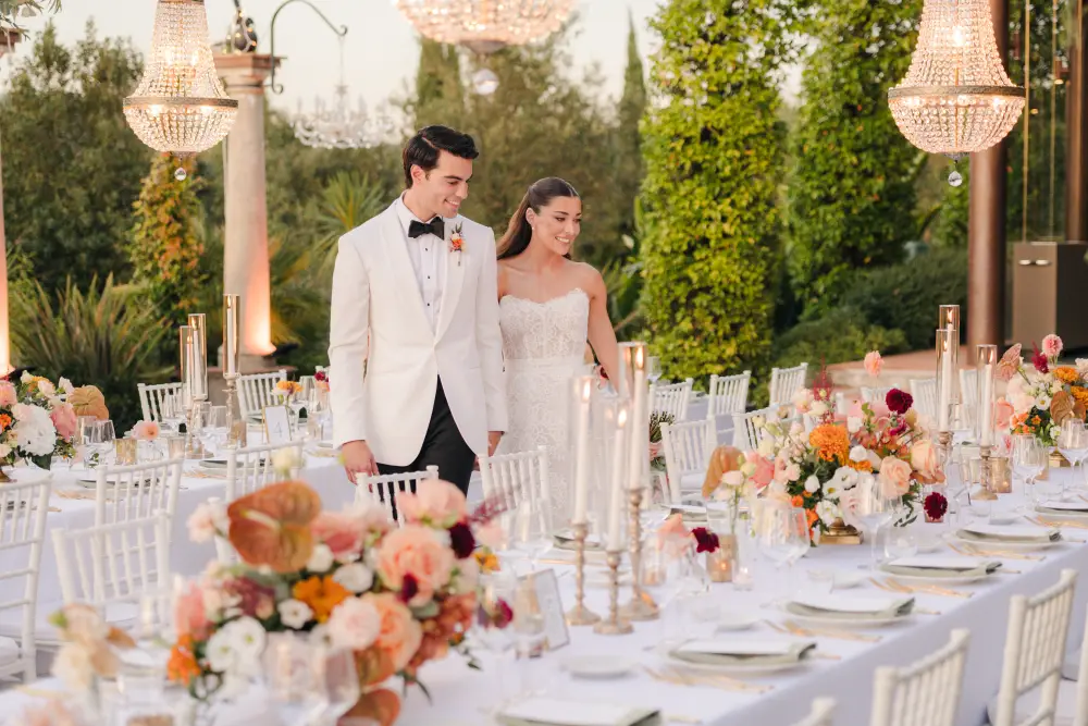 Bride and groom standing beside an elegant outdoor wedding reception table in Tuscany